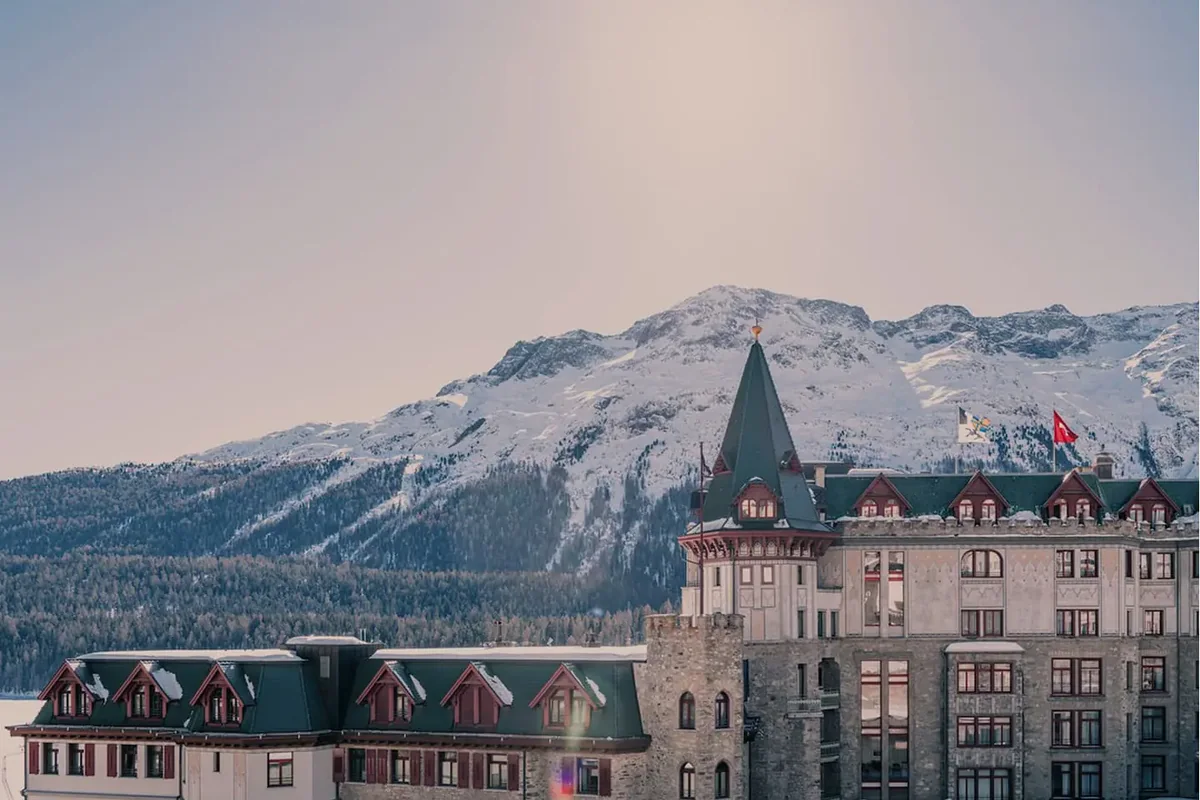 Hotel de arquitetura clássica diante de montanhas cobertas de neve