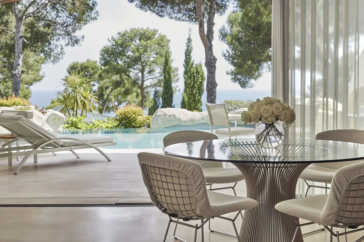 Sala de jantar clara aberta para um terraço e jardins diante do Mediterrâneo